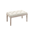 Pouf élégant en velours beige avec piétement en bois blanc sculpté.